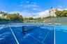 Professional tennis courts featuring vibrant blue hard courts with white line markings, regulation net systems, and full perimeter fencing