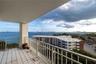 Covered balcony featuring white tiled flooring and a metal railing, overlooking the water and shoreline