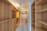 Walk-in closet featuring extensive custom wood-finish shelving, integrated wardrobe hanging rods, a built-in drawer stack, a dedicated storage bench, 