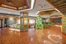Spacious interior featuring terra-cotta tile flooring, wood-paneled tray ceilings with integrated lighting, custom stone accent walls, and mirrored su