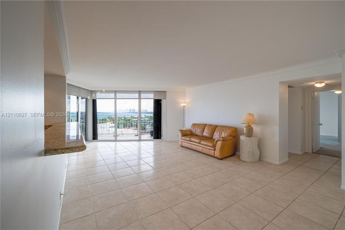 Open-concept interior featuring large-format tile flooring, floor-to-ceiling glass wall, built-in stone-surface breakfast bar, and recessed lighting