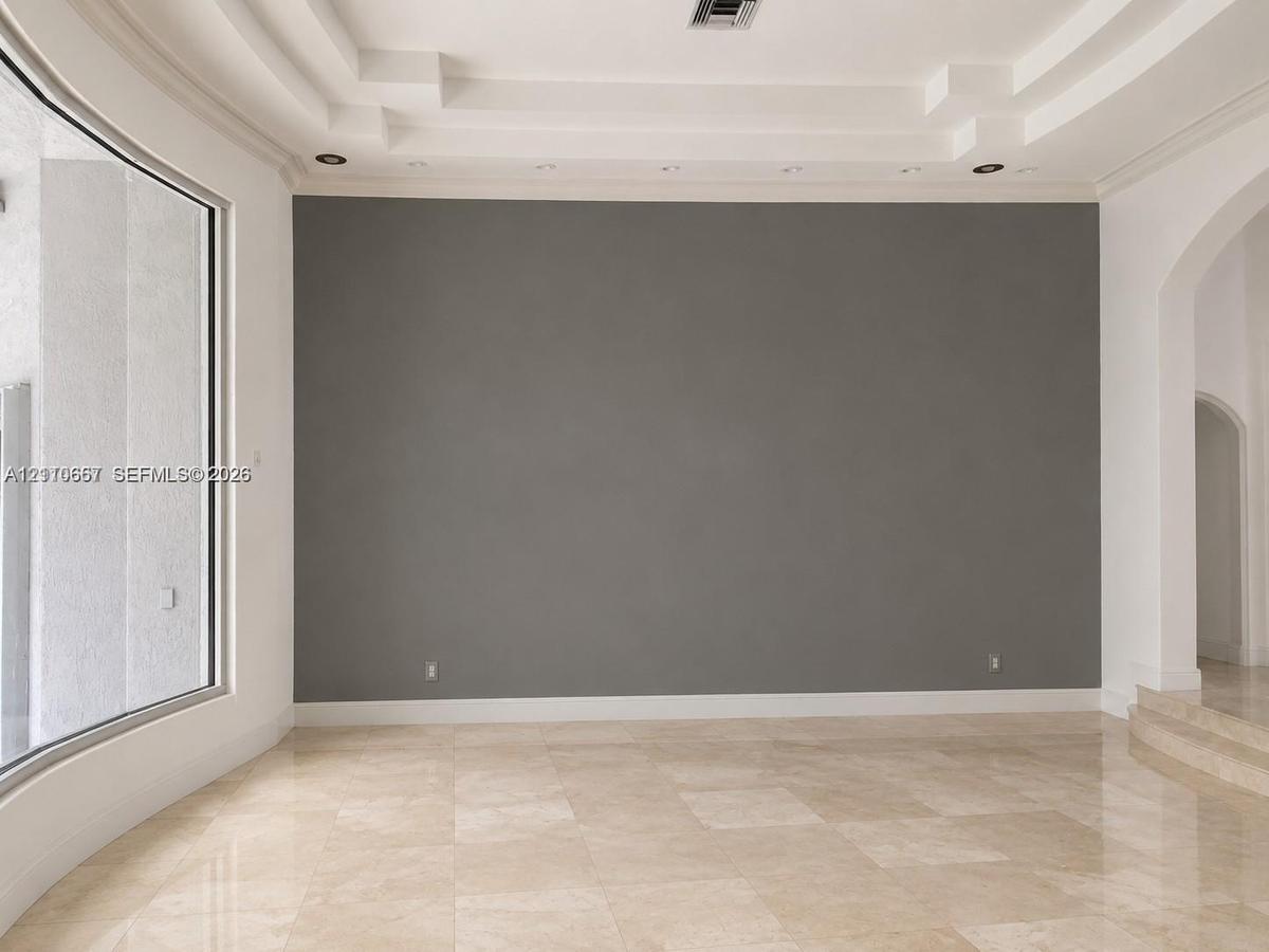 Interior space featuring multi-tiered tray ceiling, large-format polished stone flooring, expansive floor-to-ceiling windows, recessed lighting, and a