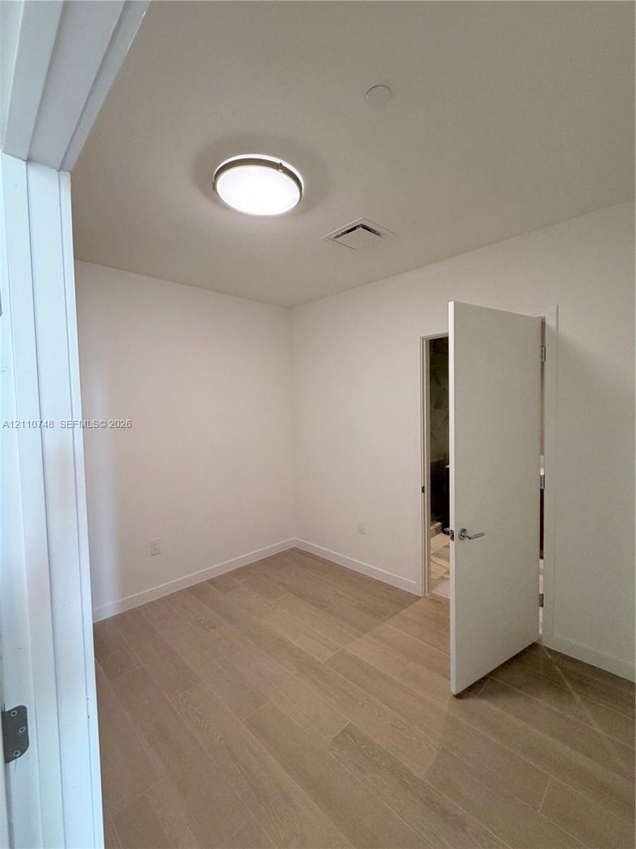 Neutral wall tones, wood-finish flooring, and a flush-mount ceiling light fixture