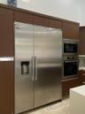 Floor-to-ceiling cabinetry with a wood-finish, stainless steel side-by-side refrigerator, built-in microwave, and wall oven