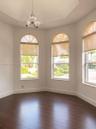 Octagonal tray ceiling featuring a central three-light pendant fixture, wood-finish flooring, and three arched windows