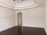 Room featuring a tray ceiling, arched entryway, and dark wood-finish flooring