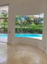 Large bay windows featuring expansive glass panels, stone-finish tile flooring, and direct exterior exposure to a swimming pool and landscaped grounds