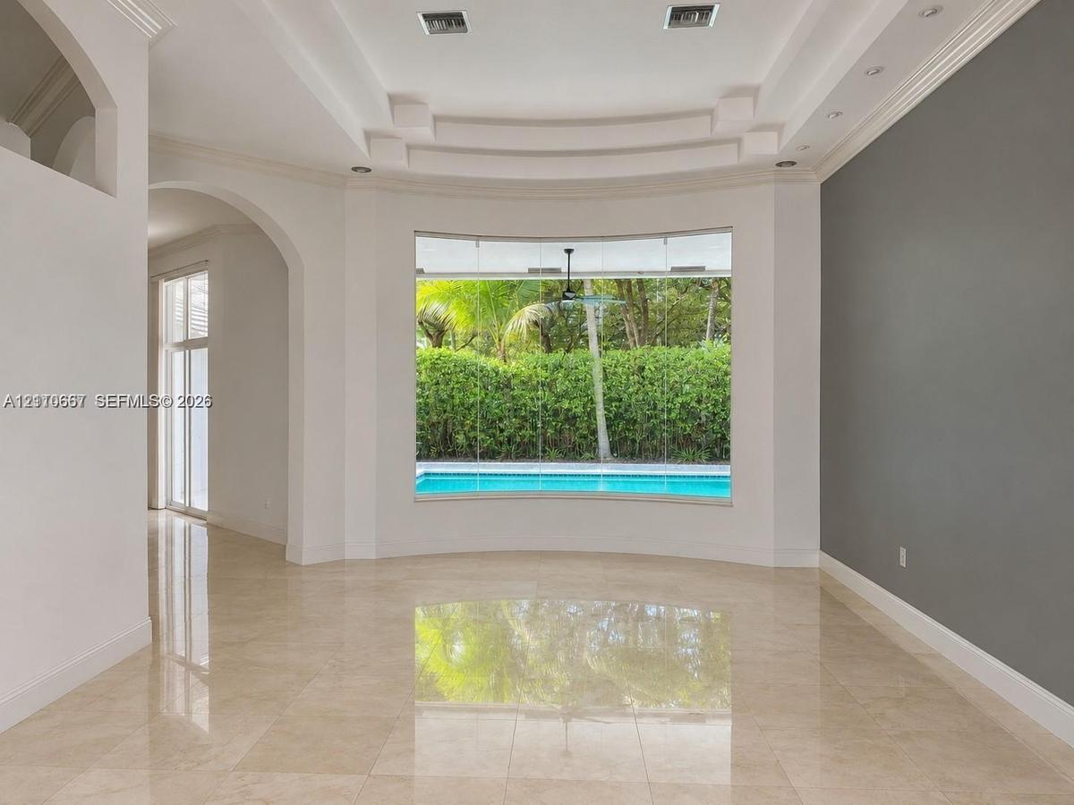 Living area featuring polished tile flooring, a recessed tray ceiling with integrated lighting, and a floor-to-ceiling picture window overlooking a sw