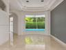 Living area featuring polished tile flooring, a recessed tray ceiling with integrated lighting, and a floor-to-ceiling picture window overlooking a sw