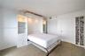 Custom white built-in cabinetry featuring integrated recessed lighting, four drawers, and shelving, paired with white louvered closet doors and carpet