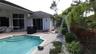 Rear patio featuring concrete paver decking, swimming pool with integrated stairs, and exterior wall-mounted lighting