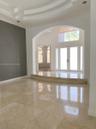 Grand foyer featuring polished stone flooring, a multi-tiered tray ceiling, an arched entryway, and double front doors with an overhead arched window