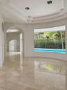 Interior featuring polished stone flooring, recessed tray ceiling, arched architectural detailing, and a expansive curved picture window showcasing a 