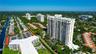 Aerial perspective of a high-rise residential structure featuring tiered balconies, covered parking areas, manicured grounds, and immediate access to 