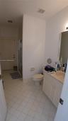 Bathroom featuring a vanity with integrated sink and stone-finish countertop, white cabinetry, framed mirror, and a shower stall with glass enclosure