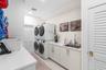 Laundry room featuring stacked washer and dryer units, solid-surface countertops, an undermount stainless steel sink with a high-arch faucet, custom f
