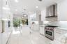 Kitchen featuring white Shaker-style cabinetry, a central island with a stone-finish countertop, stainless steel professional-grade range, full-height