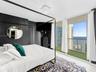 Floor-to-ceiling windows featuring access to a private balcony, custom wall-mounted lighting, and large-format tile flooring