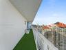 Private covered balcony featuring synthetic turf flooring and a white metal safety railing