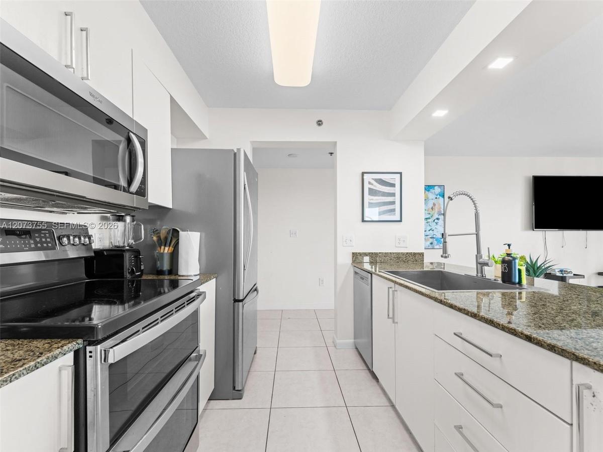 Kitchen featuring white cabinetry, stone-surface countertops, stainless steel appliances, tile flooring, and a gooseneck faucet