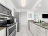 Kitchen featuring white cabinetry, stone-surface countertops, stainless steel appliances, tile flooring, and a gooseneck faucet