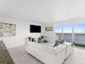 Living area featuring neutral-toned tile flooring, floor-to-ceiling glass sliding doors, and a private balcony with metal railing