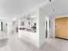 Kitchen featuring a granite countertop peninsula, high-gloss white cabinetry, recessed lighting, and tile flooring throughout the common area