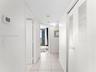 Hallway featuring tile flooring, louvered-panel closet doors, and a digital thermostat