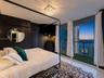 Floor-to-ceiling sliding glass doors providing access to a balcony with turf flooring and a metal railing, square crystal-accented flush mount lightin
