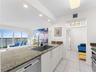Kitchen featuring a stone countertop, stainless steel under-mount sink, gooseneck faucet, white cabinetry, and a built-in stainless steel dishwasher