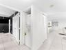 Dedicated laundry alcove with a stacked washer and dryer unit, neutral ceramic tile flooring, and white louvered bifold doors