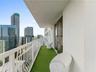 Private balcony featuring white metal railings, synthetic turf flooring, and sliding glass door access