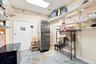 Storage area featuring wall-mounted adjustable shelving, a commercial-grade stainless steel refrigerator, drop ceiling with recessed lighting, and pai