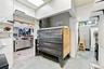 Commercial kitchen featuring a multi-deck industrial oven, stainless steel food preparation surfaces, tiled wall finishes, and recessed ceiling lighti