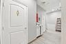 Hallway featuring wood-finish tile flooring, white shaker-style cabinetry, and molded panel doors with metallic hardware