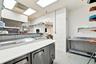 Commercial kitchen space featuring stainless steel refrigerated under-counter units, solid surface prep counters, wall-mounted stainless steel shelvin
