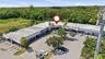 Commercial plaza featuring a U-shaped building design, expansive paved parking area, mature landscaping, and prominent signage space