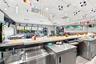 Commercial kitchen workspace featuring an extensive stainless steel countertop, professional-grade stainless steel cabinetry, a built-in stainless ste