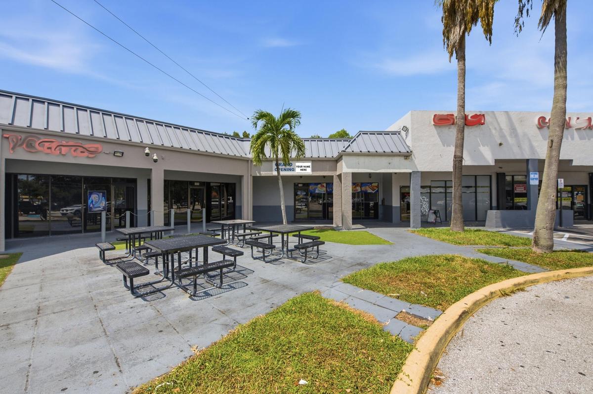 Commercial storefronts featuring metal roofing, concrete walkways, and established palm trees