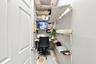 Storage space featuring multi-level white wall-mounted shelving and a built-in work surface