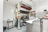 Commercial kitchen space featuring stainless steel preparation counters, a heavy-duty exhaust hood, industrial gas range, and wall-mounted shelving