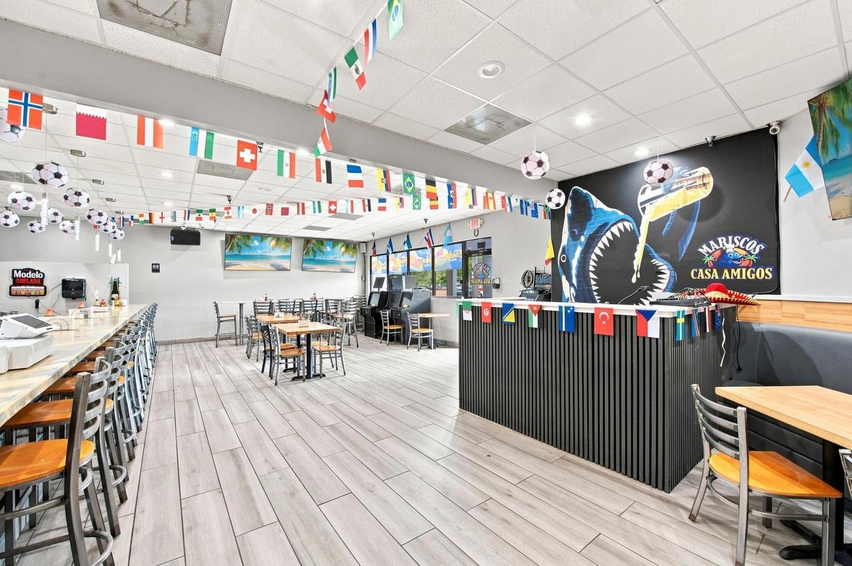 Open-concept interior space featuring wood-finish tile flooring, a built-in service counter with vertical slat detailing, and a drop-tile ceiling with
