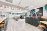 Open-concept interior space featuring wood-finish tile flooring, a built-in service counter with vertical slat detailing, and a drop-tile ceiling with