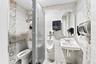 Restroom featuring wood-finish wall tile, patterned decorative tile accents, wall-mounted porcelain sink, wall-mounted urinal, and metal safety grab b