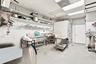 Commercial kitchen featuring stainless steel multi-basin sinks, wall-mounted open shelving, a walk-in cooler, and tiled wall surfaces
