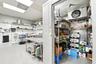 Commercial food preparation area featuring a walk-in cooler, stainless steel work table, drop ceiling with recessed lighting, and industrial metal she