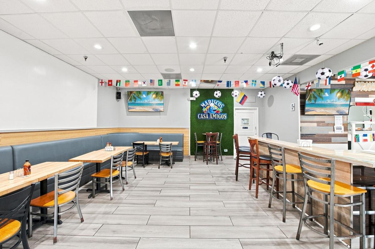 Commercial dining area featuring tile flooring, built-in wall-mounted bench seating, a wood-finish bar counter, and recessed lighting