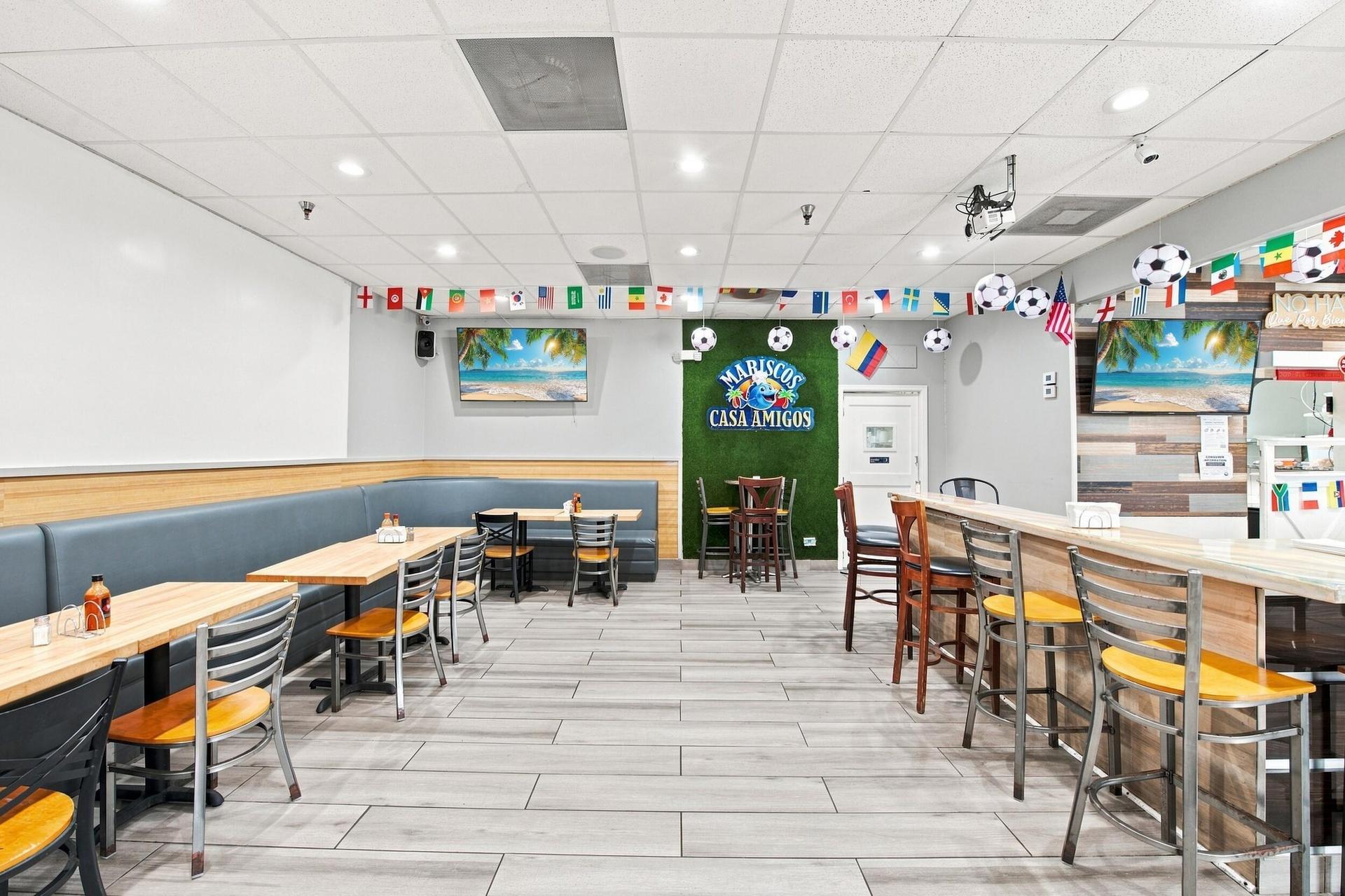 Commercial dining area featuring tile flooring, built-in wall-mounted bench seating, a wood-finish bar counter, and recessed lighting