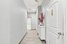 Hallway featuring wood-finish tile flooring, recessed ceiling panels, and white-painted interior doors