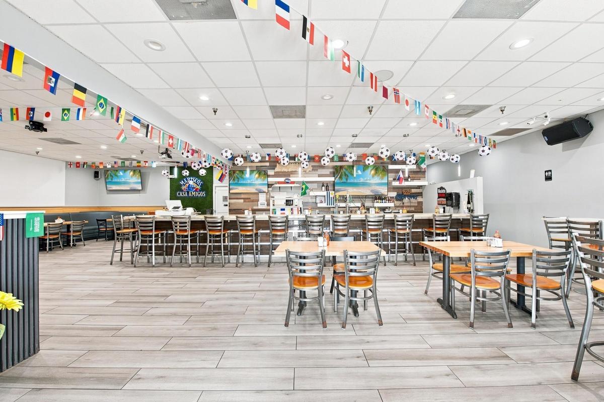 Spacious interior featuring wood-finish flooring, a full-length service bar with professional shelving, recessed lighting, and a textured wood-panel a